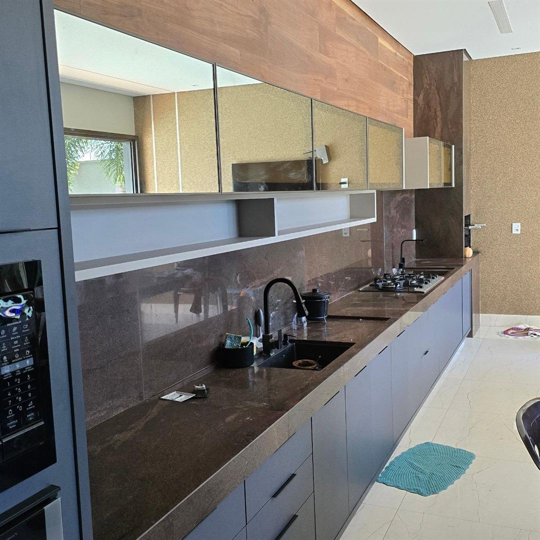 Cozinha planejada linear com armários grafite, aéreos de vidro e painel de madeira até o teto
