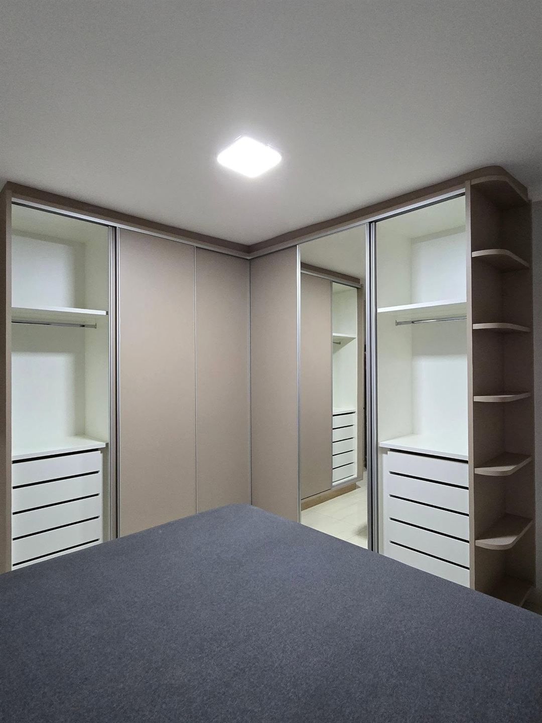 Guarda-roupa planejado aberto mostrando cabideiros, prateleiras e gavetas brancas