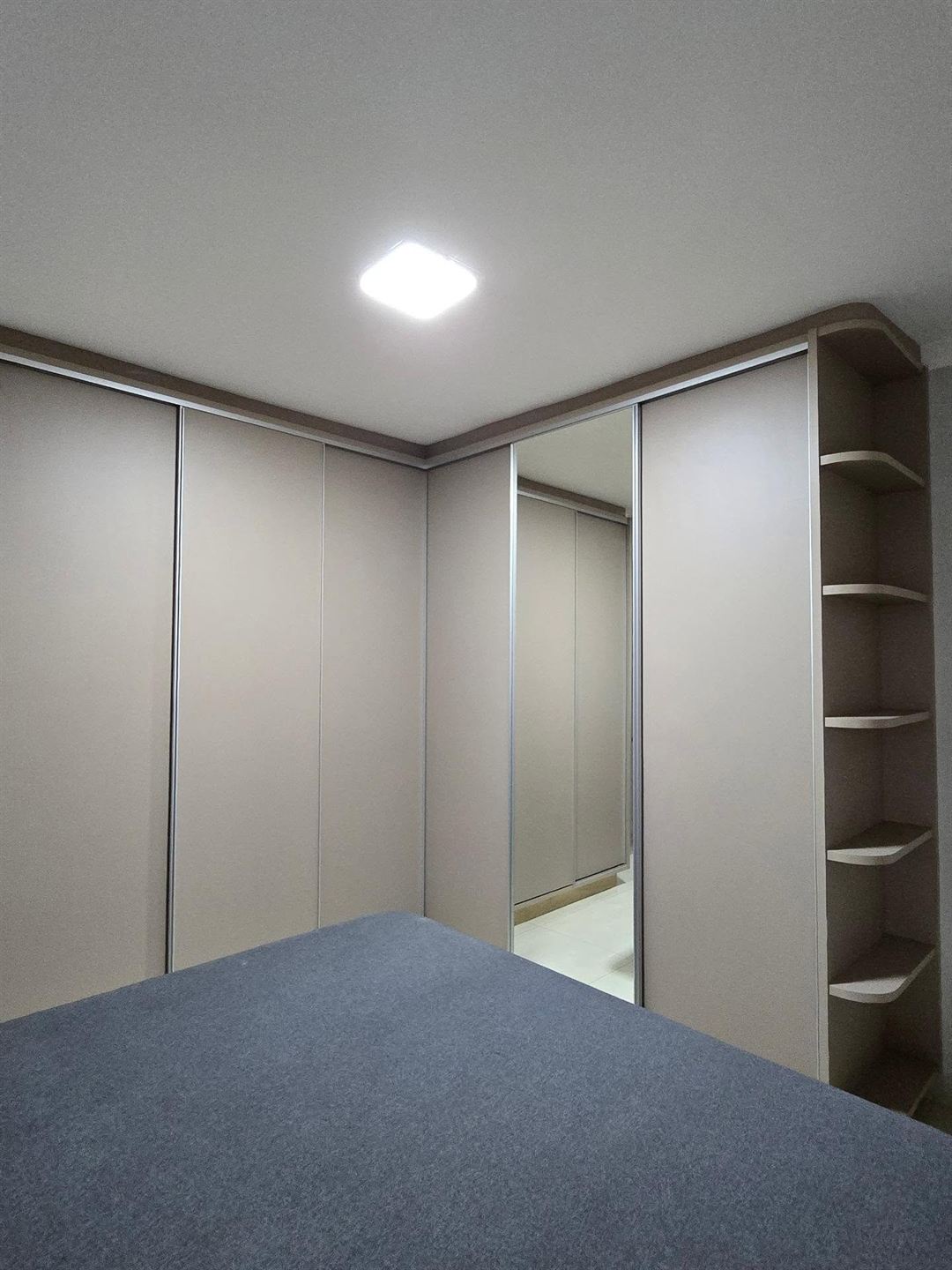 Guarda-roupa planejado de canto em tom fendi com portas de correr