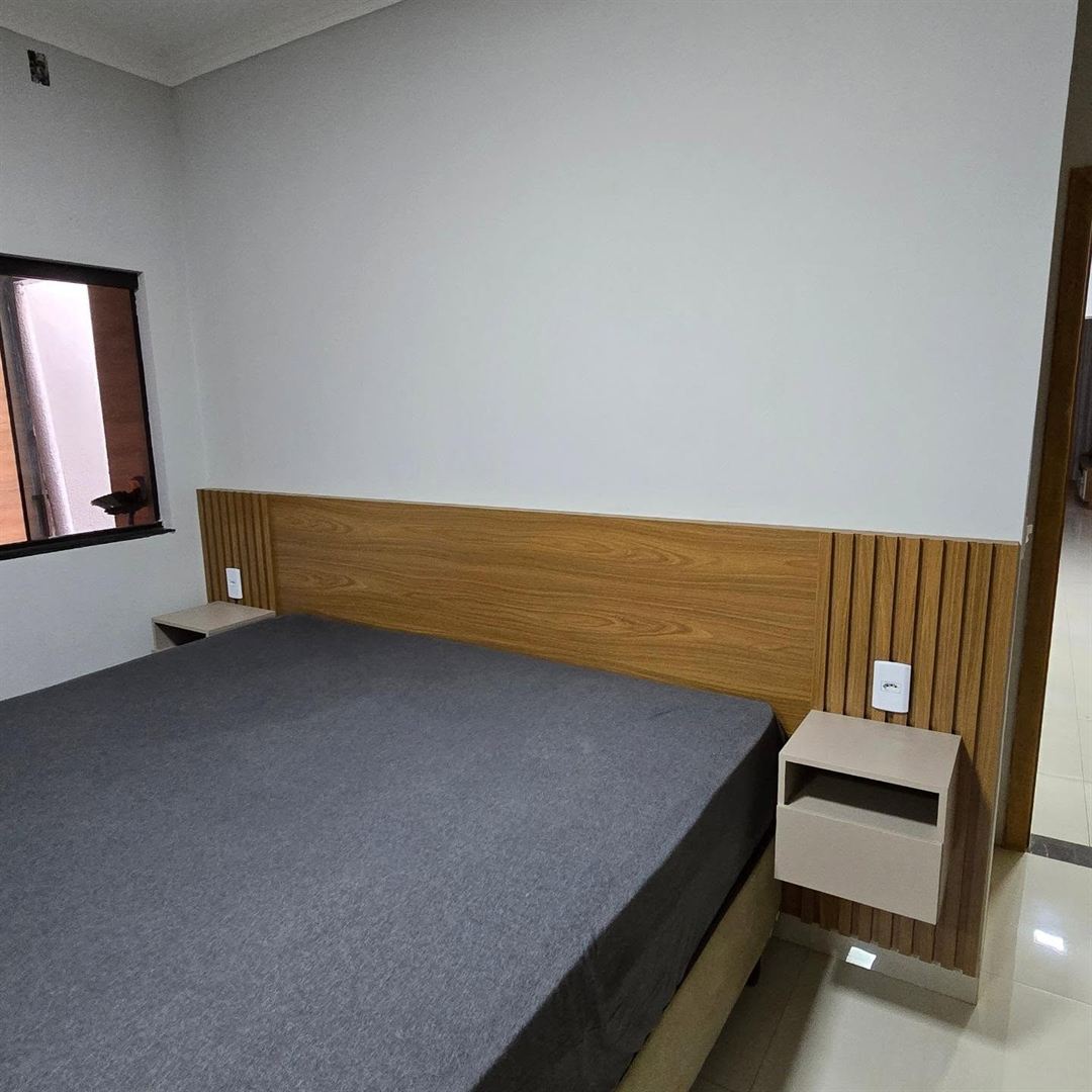 Quarto planejado com painel de cabeceira em madeira, ripado lateral e criado-mudo suspenso